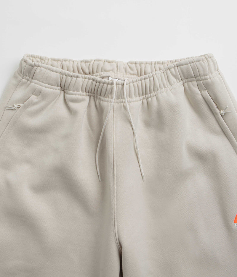 Nike ACG Tuff Fleece Lungs Pants in Light Orewood Brown and Hyper Crimson